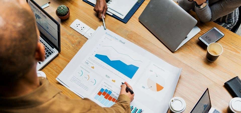 Google Adwords çalışmaları bulunur sarı masanın üstünde bulunan bilgisayar ve insanların kalemlerinin yanında